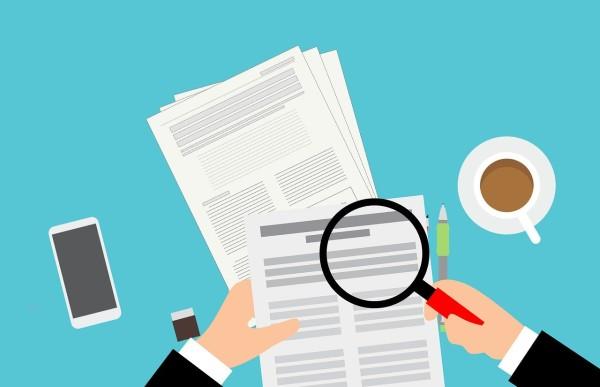 Digital illustration showing two hands, one holding a magnifying glass to look at papers full of text (Image by Mohamed Hassan from Pixabay)
